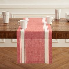 a red and white striped table runner on a wooden table with coffee cups in the background