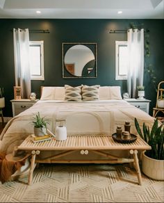 a bed room with a neatly made bed next to a table and potted plants