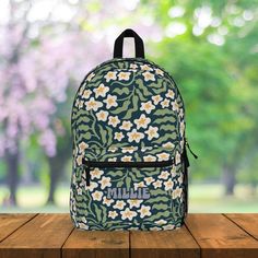 Introducing our stunning Boho Floral Backpack, featuring delicate white flowers and lush green foliage against a striking dark blue background. This stylish backpack is not only a fashion statement but also a functional everyday essential. With the option to customize with your name in a variety of locations, make it uniquely yours. The backpack is designed for comfort with padded straps, while offering convenience with a front zip pocket and an inside laptop pocket. Stay organized and on-trend with this versatile and chic accessory. | PRODUCT DETAILS | Padded mesh back panel and straps for extra comfort 4 Compartments - 1 main zip pocket, 1 front pocket, bottle pocket on the side, inside compartment for laptop or tablet Zipper closure for three main pockets | SIZES | 11.81"L x 5.12"W x 18 Green Backpack For Back To School Gift, Personalized Green Travel Bag, Everyday Customizable Rectangular Backpack, Personalized Everyday Backpack, Personalized Rectangular Backpack For Travel, Casual Personalized Travel Backpack, Customizable Standard Backpack For Travel, Customizable Standard Backpack For Back To School, Casual Personalized Standard Backpack