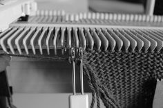 a black and white photo of a piece of fabric hanging from a hook on a sewing machine