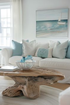 a living room with white furniture and blue pillows on the couch, along with a coffee table