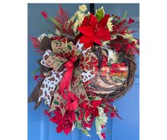 a christmas wreath with poinsettis and ribbons hanging on a blue door