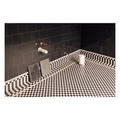 a black and white checkered floor in a bathroom with two faucets on the wall