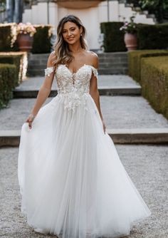 a woman in a white wedding dress is walking down the street with her hand on her hip