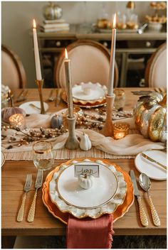 the table is set with gold and white plates, silverware, candles, and napkins