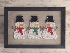 three snowmen made out of yarn in a frame