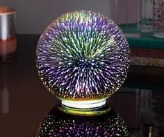 a colorful glass ball sitting on top of a table next to a candle and vase