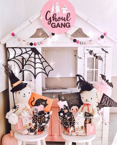 two white chairs with halloween decorations on them in front of a doll house and sign that says ghost gang