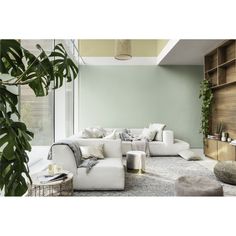 a living room filled with lots of white furniture and plants in the middle of it