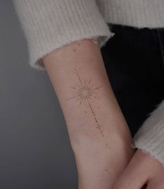 a woman's arm with a small star tattoo on it