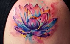 a woman's back shoulder with a watercolor lotus tattoo on it