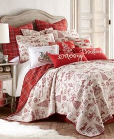 a red and white comforter set with christmas decorations on the bed, along with pillows