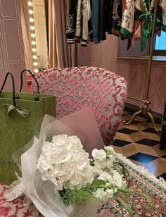 white flowers are sitting in a vase on a table next to a green shopping bag