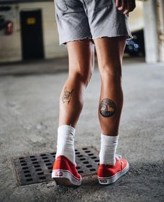 a person with tattoos standing on a skateboard