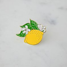 A Hester & Cook Lemon Enamel Pin adorned with leaves. Yellow Enamel Brooches For Gifts, Fresh Fruits, A Metal, Enamel Pin, Gold Finish, Enamel Pins, Lemon, Great Gifts, Gold