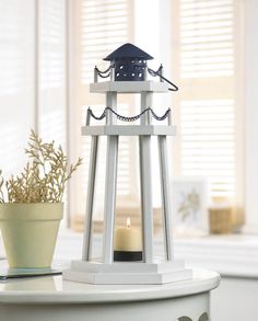 a white candle holder sitting on top of a table next to a potted plant