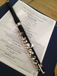 a black and silver flute resting on top of a piece of paper with writing underneath it