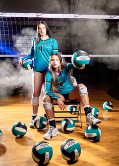 two girls are posing with volleyballs on the court