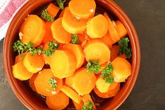 a bowl filled with carrots and parsley on top of a table next to a towel