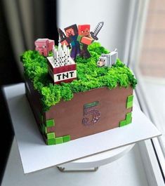 a cake made to look like a box with people and animals on it sitting in front of a window