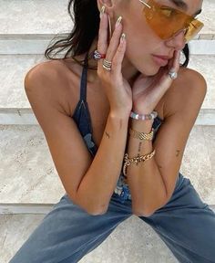 a woman sitting on the steps with her hands to her face and wearing gold jewelry