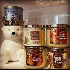 a white teddy bear sitting next to some candles and a candle holder on a shelf