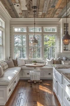 a kitchen with white cabinets and wooden floors, windows above the sink, and a breakfast nook