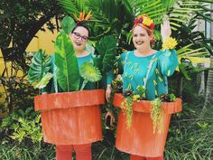 two people wearing plant pots with plants in them