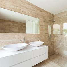 two white bowls are sitting on the counter in this modern bathroom with wooden walls and flooring