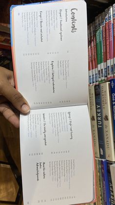 a person holding two open books in front of a book shelf