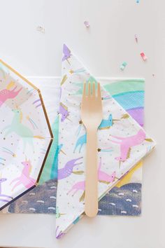 colorful unicorn napkins with wooden utensils on them