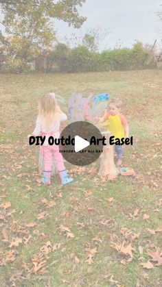 two young children are playing in the grass with an object that says, diy outside art easel