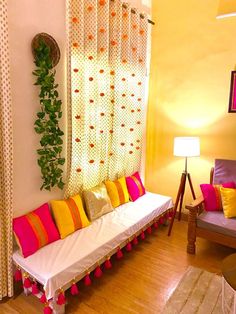 a living room filled with lots of furniture next to a window covered in colorful pillows