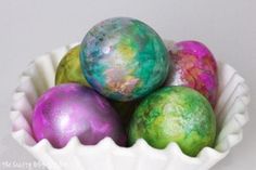 four painted easter eggs in a white bowl