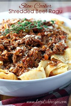 a white bowl filled with pasta covered in beef ragu and topped with parmesan cheese