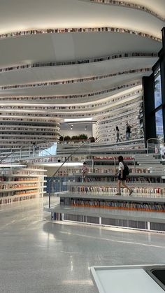 people are walking up and down the escalator in a library with bookshelves