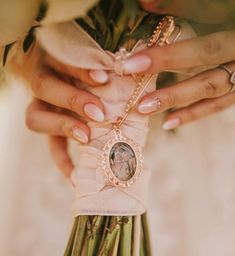 the bride is holding her bouquet with an oval locke on it's clasp and ring