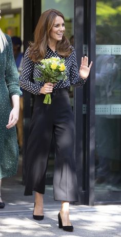 the duke and duchess of cambridge are walking down the street with flowers in their hands