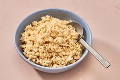 a blue bowl filled with rice and a spoon on top of a pink tablecloth