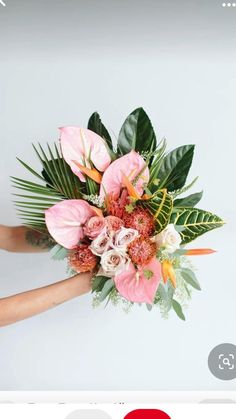 a woman holding a bouquet of flowers in her hands with white wall and background behind