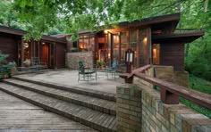 a house with steps leading up to the front door and patio area, surrounded by trees