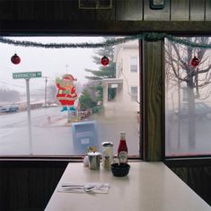 a table with two cups and bottles on it in front of a window that has christmas decorations hanging from the windows