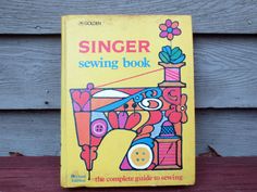 a yellow book with an image of a sewing machine on the front cover that says singer sewing book