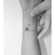 a small cactus tattoo on the left inner forearm and wrist is shown in this black - and - white photo