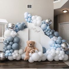 a teddy bear sitting on top of a giant balloon arch with balloons and decorations around it