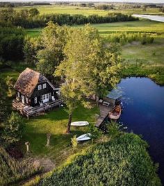 an aerial view of a house with boats in the water and trees around it,