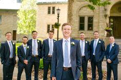 a group of men standing next to each other in front of a building with trees