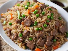 a white plate topped with rice and meat next to chopsticks on a table