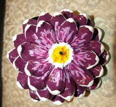 a purple and white flower sitting on top of a table