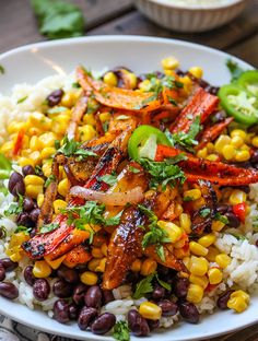 a white bowl filled with rice, beans and veggies on top of a wooden table